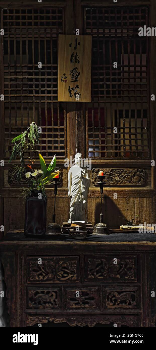 White Buddha statuettehome altar with flowersplantstwo candles