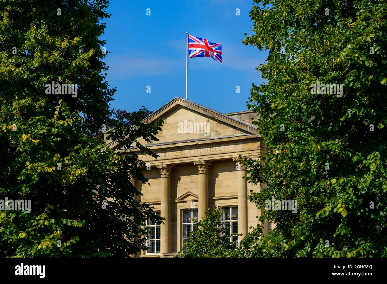 Union Jack flag flying over sunlit Harrogate council offices (Latin motto, building exterior, deep blue sky) - Crescent Gardens, Yorkshire England, UK Stock Photo
