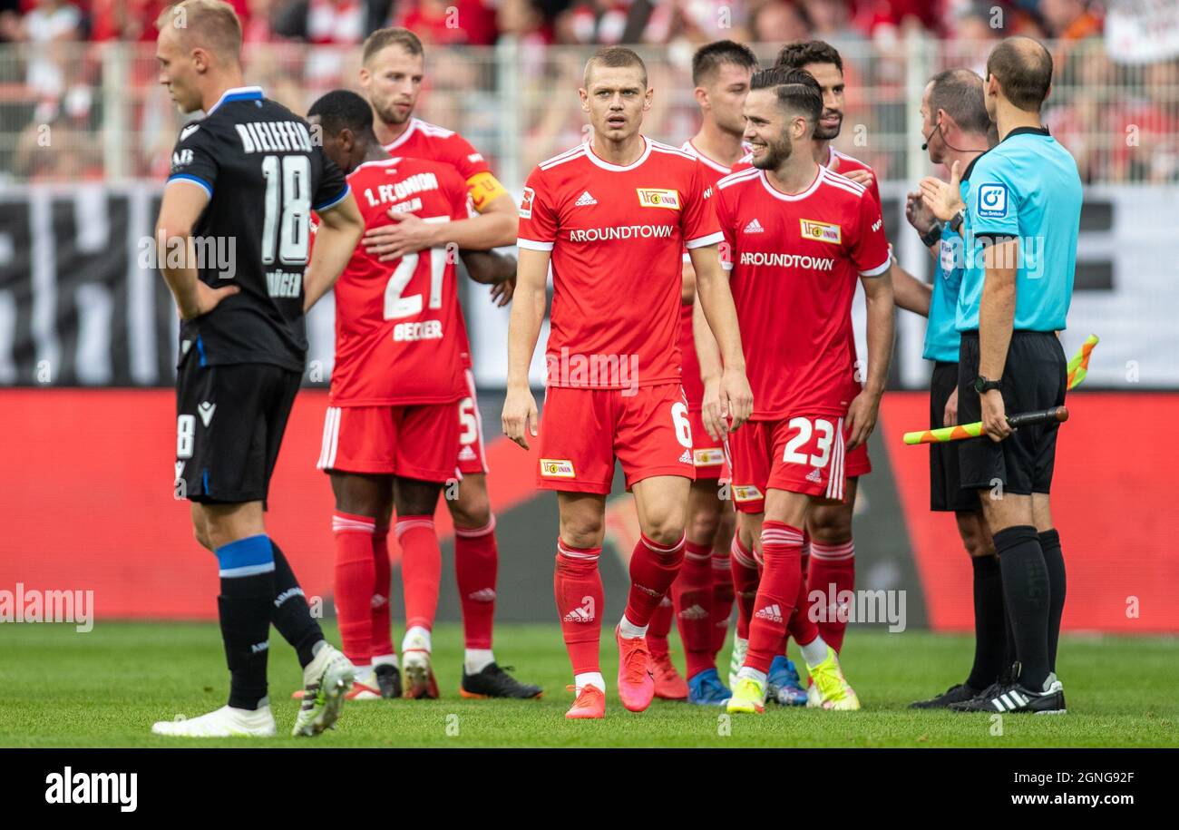 25 September 2021, Berlin: Football, Bundesliga, Matchday 6, 1. FC Union Berlin - Arminia Bielefeld, Stadion An der Alten Försterei: Berlin's Sheraldo Becker (2nd from left-r) and teammates Marvin Friedrich, Julian Ryerson and Niko Gießelmann cheer after the victory. Arminia Bielefeld's Florian Krüger (l) walks off the pitch in disappointment. Photo: Andreas Gora/dpa - IMPORTANT NOTE: In accordance with the regulations of the DFL Deutsche Fußball Liga and/or the DFB Deutscher Fußball-Bund, it is prohibited to use or have used photographs taken in the stadium and/or of the match in the form of Stock Photo