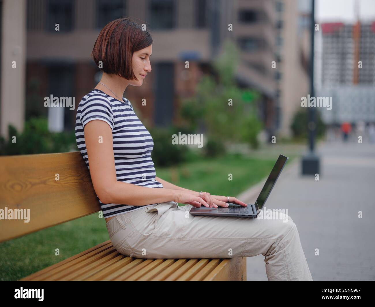 Young asian female student working at laptop sit down on bench outside ...