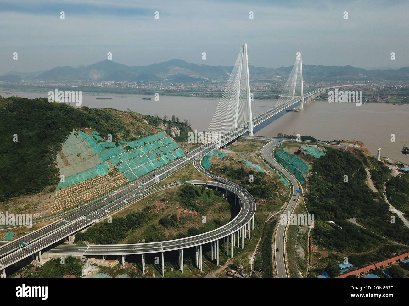 (210925) -- WUHAN, Sept. 25, 2021 (Xinhua) -- Aerial photo taken on Sept. 25, 2021 shows the Wuxue Yangtze River road bridge in central China's Hubei Province. Two new bridges over the Yangtze River opened to traffic Saturday in central China's Hubei Province. With a total length of 31 km and an 808-meter-long main span, the Wuxue Yangtze River road bridge links Wuxue City with Yangxin County of Huangshi City. The bridge has six lanes with a designed speed of 100 kph. The 11.2-km Chibi Yangtze River road bridge, with a 720-meter-long main span, shortened the vehicular travel time between Chibi Stock Photo