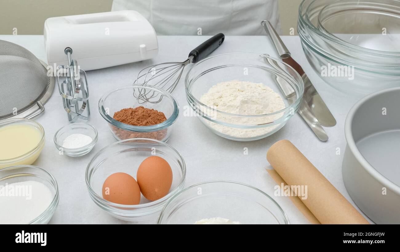 Ingrediets and dishes for making chocolate cake close up on kitchen table. Step by step chocolate cake recipe Stock Photo