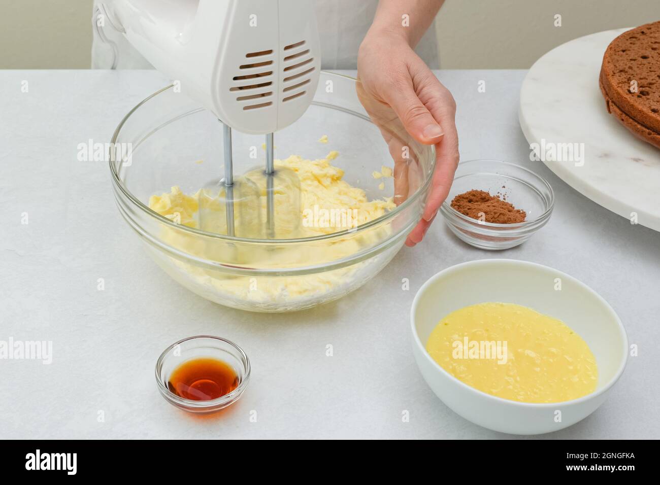 Making the chocolate cake frosting. Woman hands beating butter in a glass  bowl using an electric hand mixer, close up view Stock Photo - Alamy