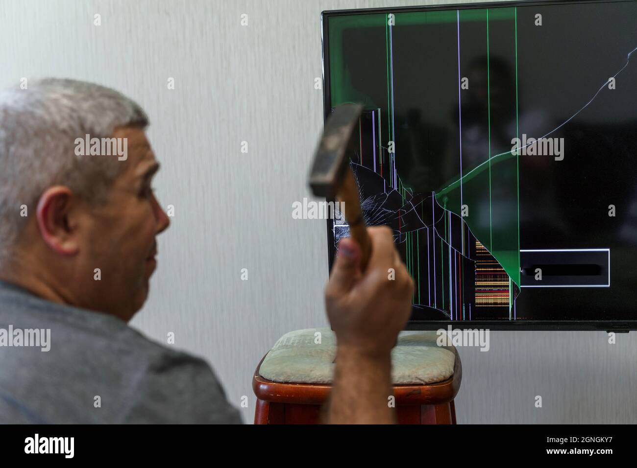man smashes the tv with a hammer. the man is not happy with the news in the media Stock Photo