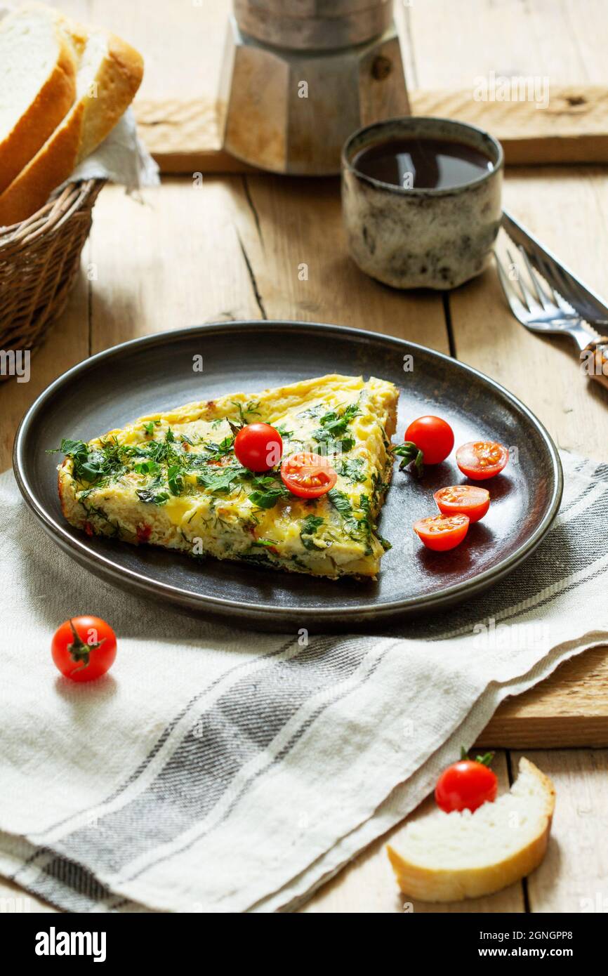 Breakfast of omelet with vegetables, herbs and cheese, served with bread and coffee. Stock Photo