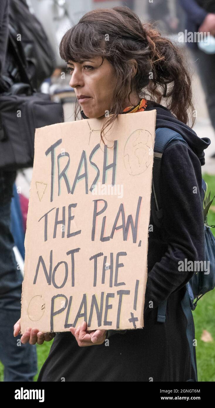 London, UK. 25th Sept 2021. A woman holds a poster 'Trash the Plan Not The Palned!' at a rally before the march to the Edmonton incinerator against plans by the North London Waste Authority to build a larger incinerator costing £1.2bn on the site in one of London's more deprived areas, increasing air pollution which already breaches legal limits. It would put 700,000 tonnes of CO2 into the atmosphere each year, incompatible with net zero targets. Incineration discourages recycling and around half of waste now burnt could be recycled. Peter Marshall/Alamy Live News Stock Photo