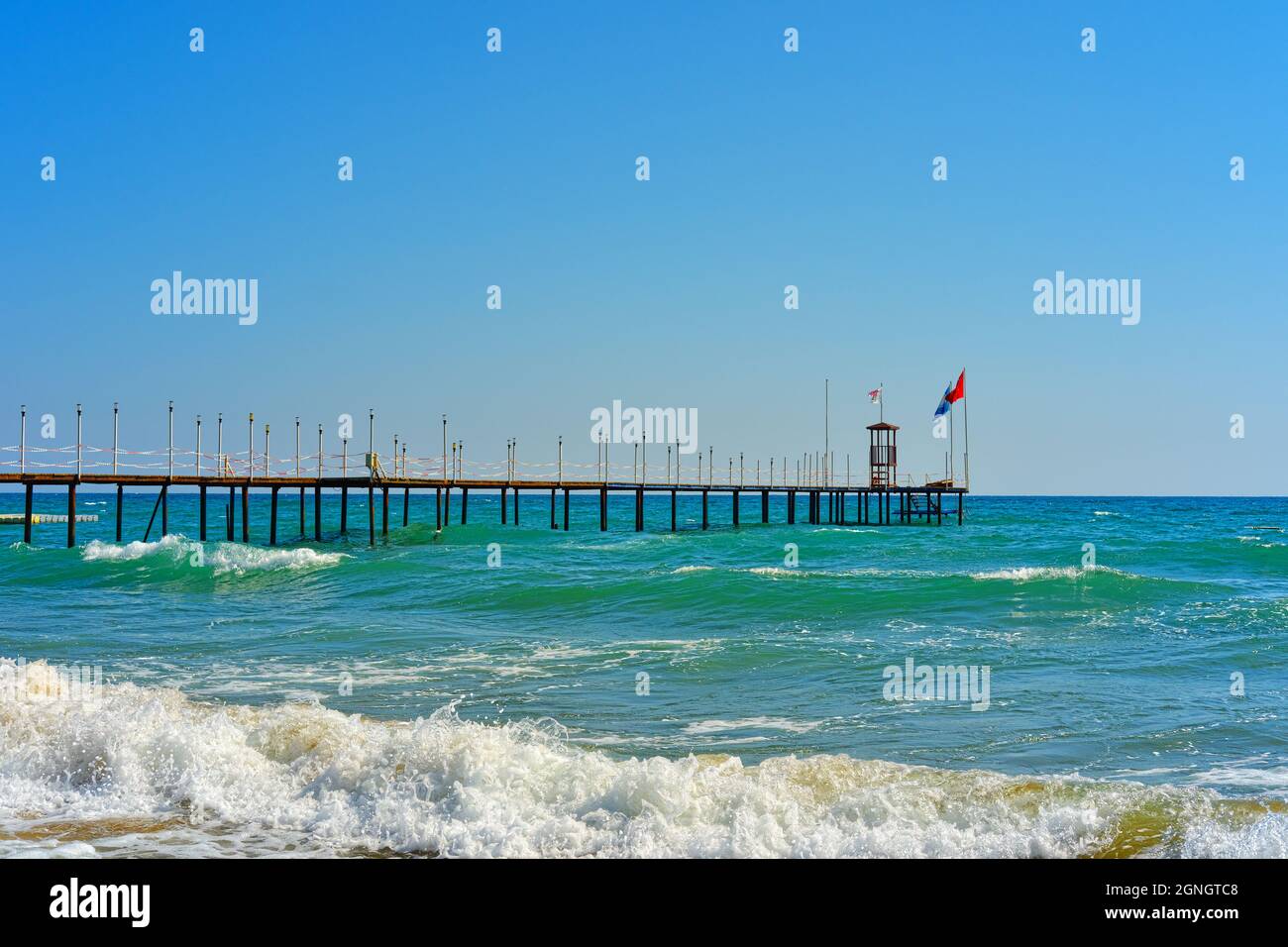 Waves at Turquoise Coast of Manavgat Antalya and Pier with Turkish flag Stock Photo
