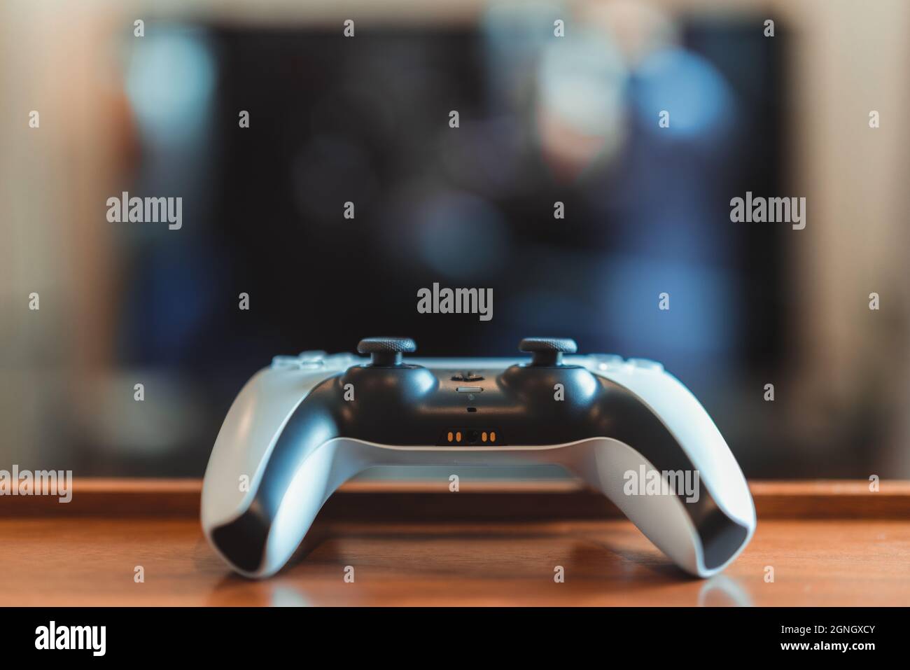 London, UK - May 25, 2021: Close up of Playstation 5 (PS5) controller on the table, tv on background, selective focus. Playstation 5 is the latest vid Stock Photo