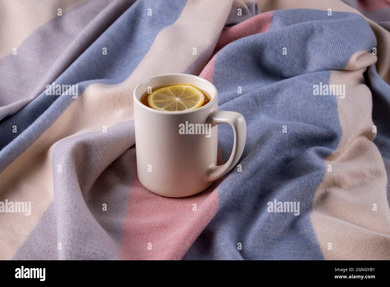 Soft warm scarf in pastel colors and ceramic mug with hot tea Stock Photo