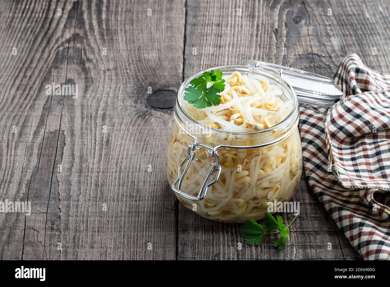 Marinated  sprouted mung beans in glass jar on wooden table Stock Photo