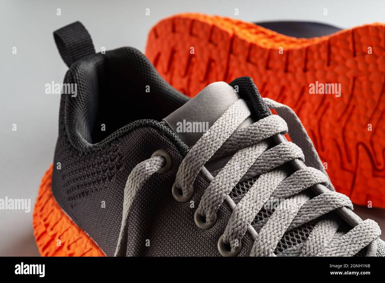 Elastic laces of gray mesh fabric sneakers with orange grooved sole close up. Lacing up the modern textile trainers for sport and active lifestyle Stock Photo Alamy