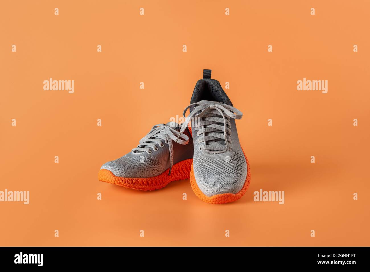 Pair of grooved orange sole sneakers from gray mesh fabric over orange  background. Laced up stylish textile trainers for active lifestyle, fitness  Stock Photo - Alamy