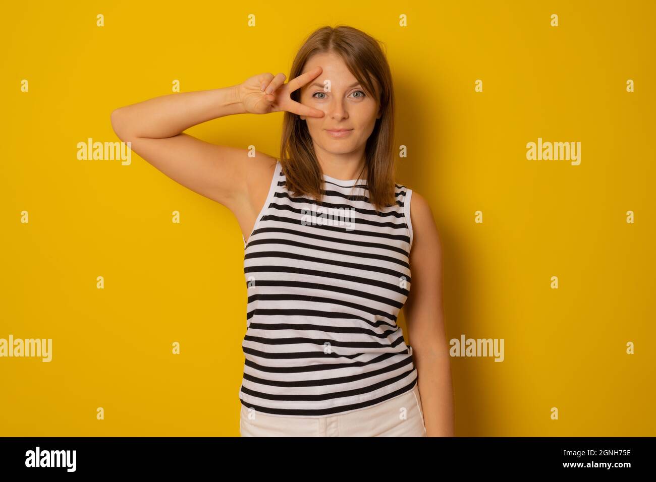 Young woman in striped shirt making victory, positive, peace sign on ...