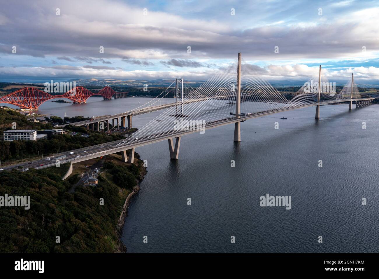 North Queensferry, Eaglesham, Scotland, UK. 25th Sep, 2021. PICTURED: Aerial drone view of Forth bridges. Spanning three centuries in bridge design and connecting two of Scotland's counties of Fife and Lothian, the Queensferry Crossing Scotland's newest bridge designed to look like sails on a ship, connects North Queensferry to South Queensferry, with Forth Road Bridge behind showcasing mid 20th century technology and background Forth Rail Bridge late 1800s with its cantilever construction. Credit: Colin Fisher/Alamy Live News Stock Photo