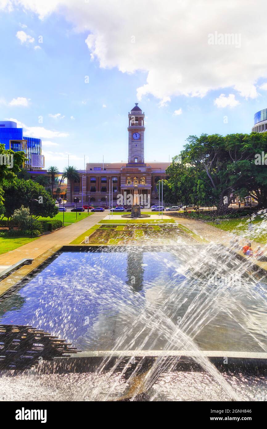 City of Newcastle in NSW, Australia - the Town Hall building and local park at midday behind fresh water fountain. Stock Photo