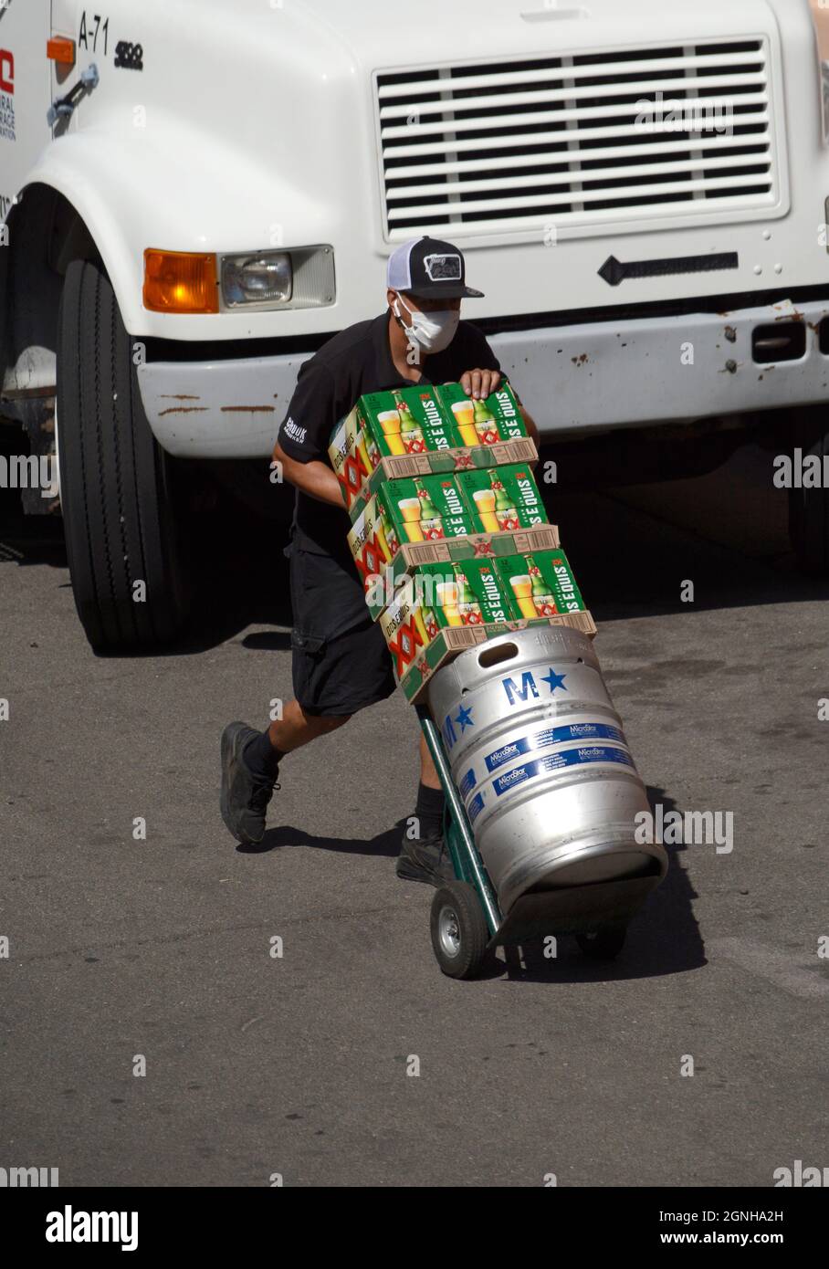 A beer deliveryman with a hand truck delivers cartons of Dos Equis