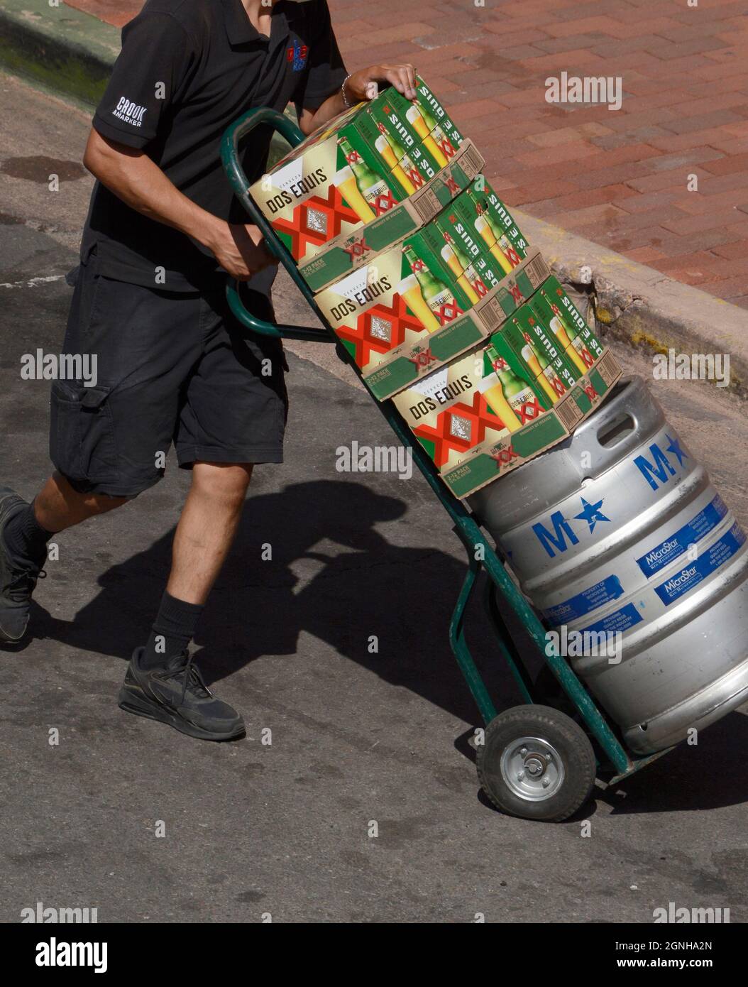 A beer deliveryman with a hand truck delivers cartons of Dos Equis