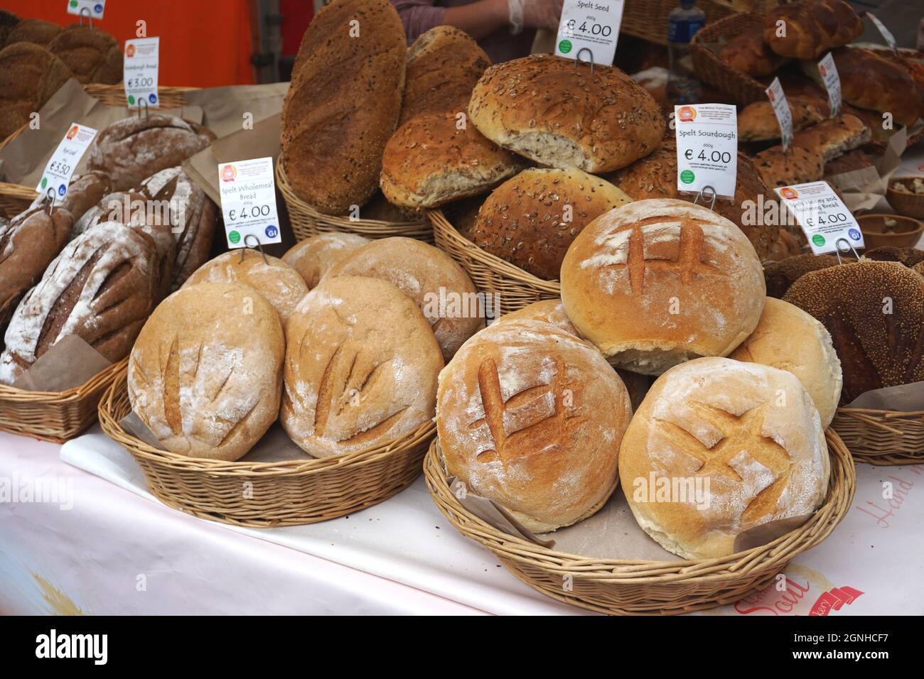 Plump loaves of wholesome artisan breads and other fresh baked goods offered for sale at an outdoor market in the seaside village of Howth, Ireland. Stock Photo