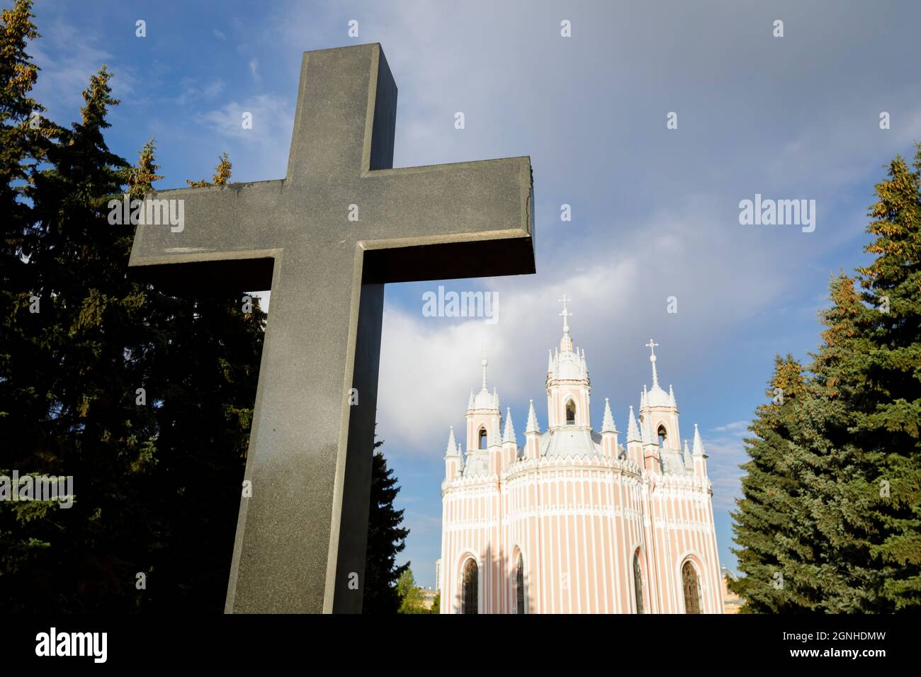 The granite cross and the Church of the Nativity of John the Baptist 'Chesmenskaya'. Russia, Saint-Petersburg, September 7, 2021 Stock Photo