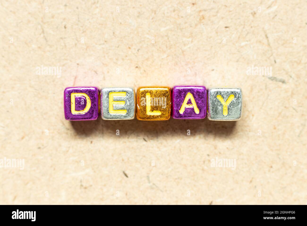 Metallic color alphabet letter block in word delay on wood background ...