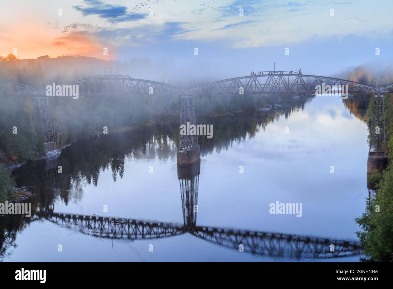 mist, autumn, river, forest landscape with reflections of a bridge during sunset Stock Photo