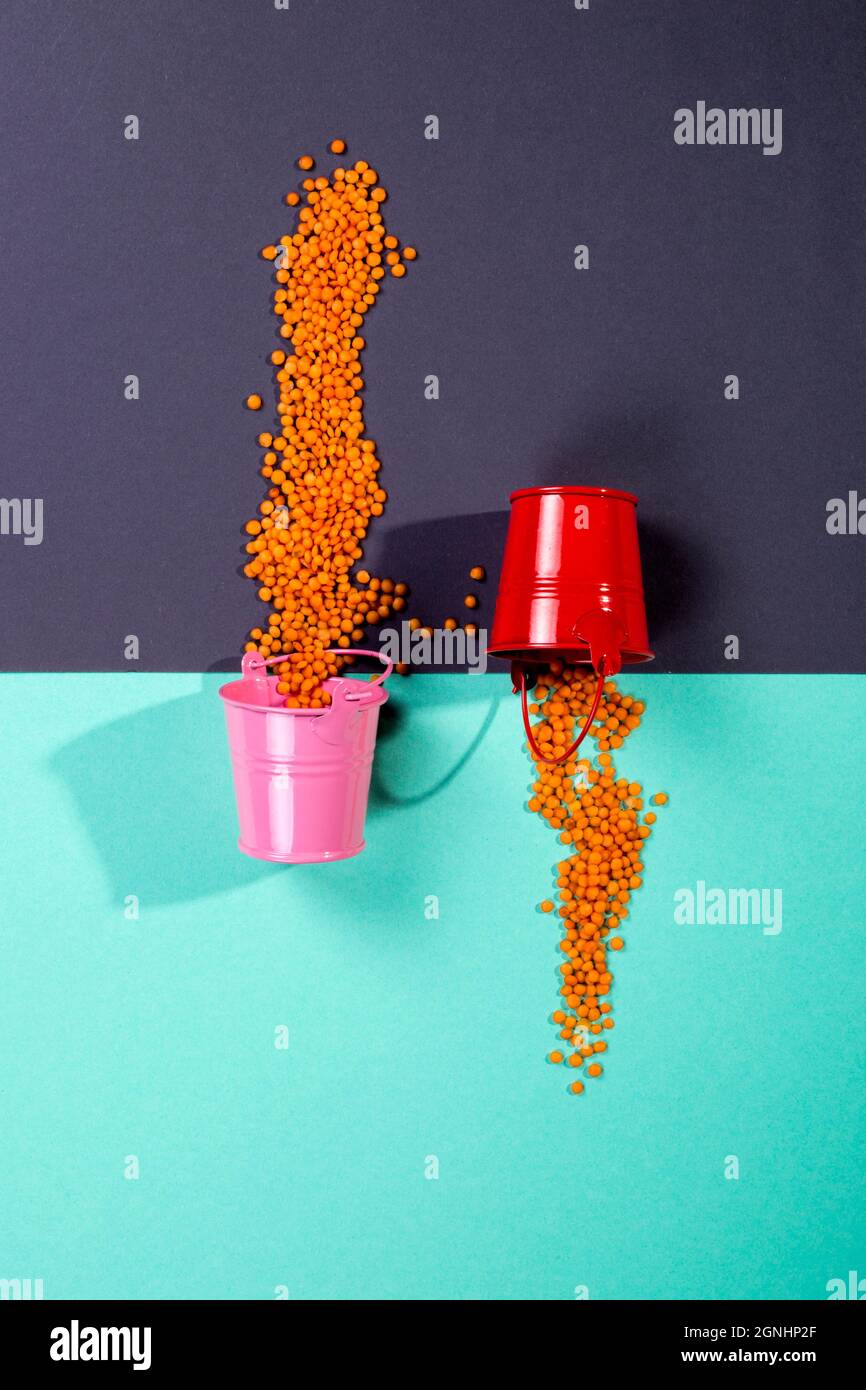 Two multicolored buckets with scattered lentil beans Stock Photo