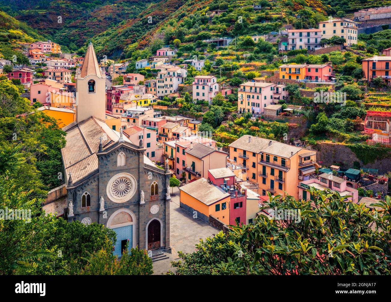 First city of the Cique Terre sequence of hill cities - Riomaggiore with tower of Church of San Giovanni Battista. Wonderful summer scene of Liguria, Stock Photo