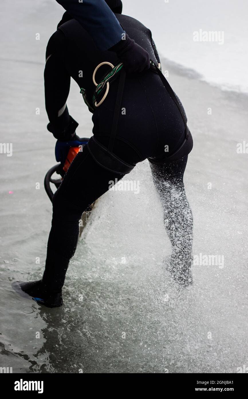 Man cutting an ice hole with a chainsaw for iceswimming Back view of