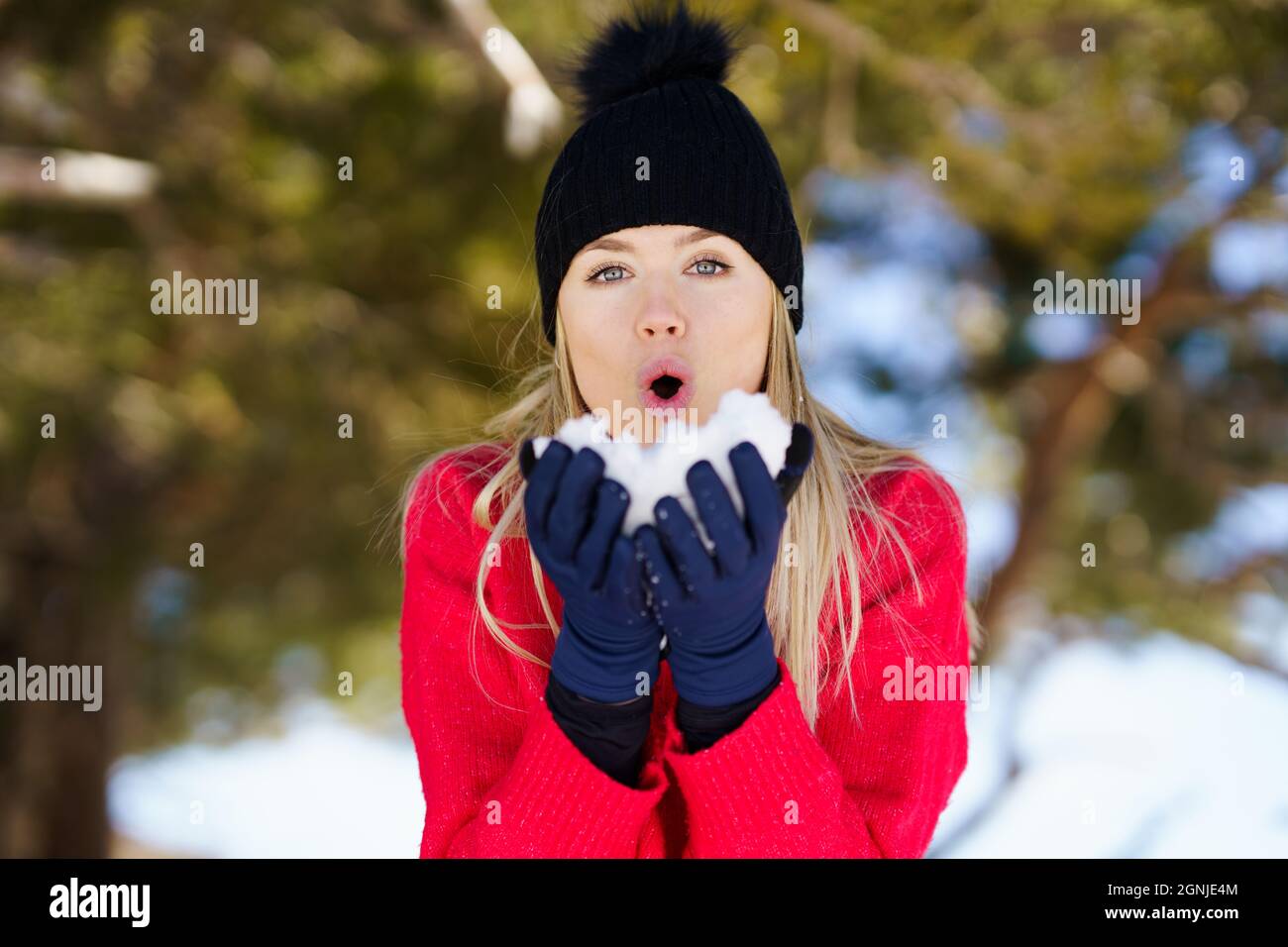 Young woman blowing a snowball in winter, in Sierra Nevada, Granada, Spain. Stock Photo