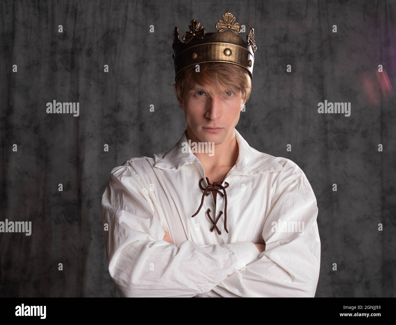 young king, man from people usurped throne, a charismatic man in a simple white blouse with lacing and with a crown on his head, a character of histor Stock Photo