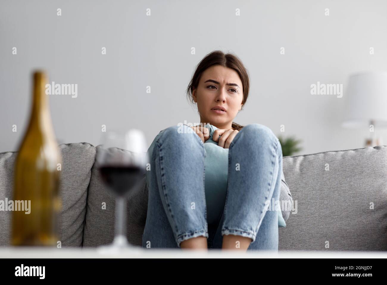 Unhappy sorrowful cute young european lady sad from problems with alcohol at home interior Stock Photo