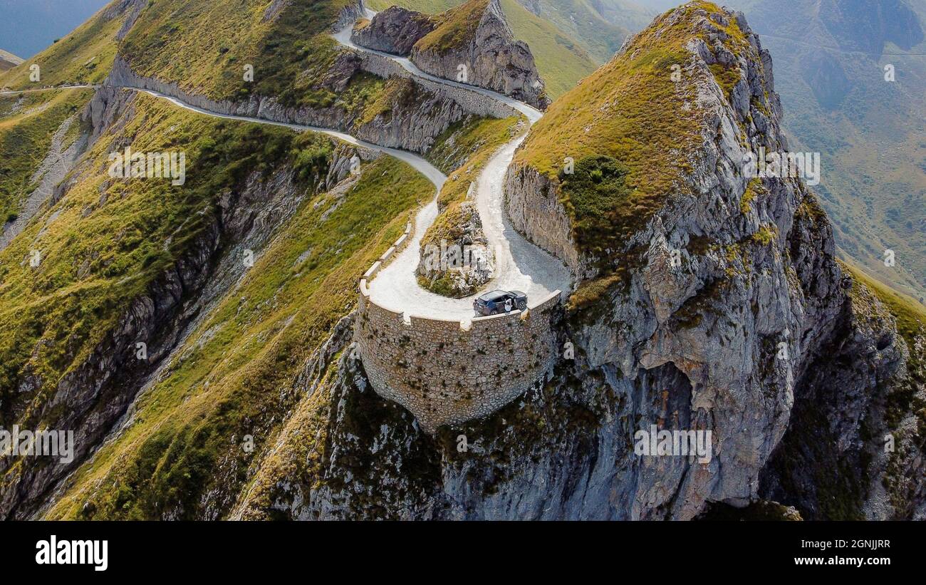An aerial view of a narrow winding road at the top of a rocky mountain