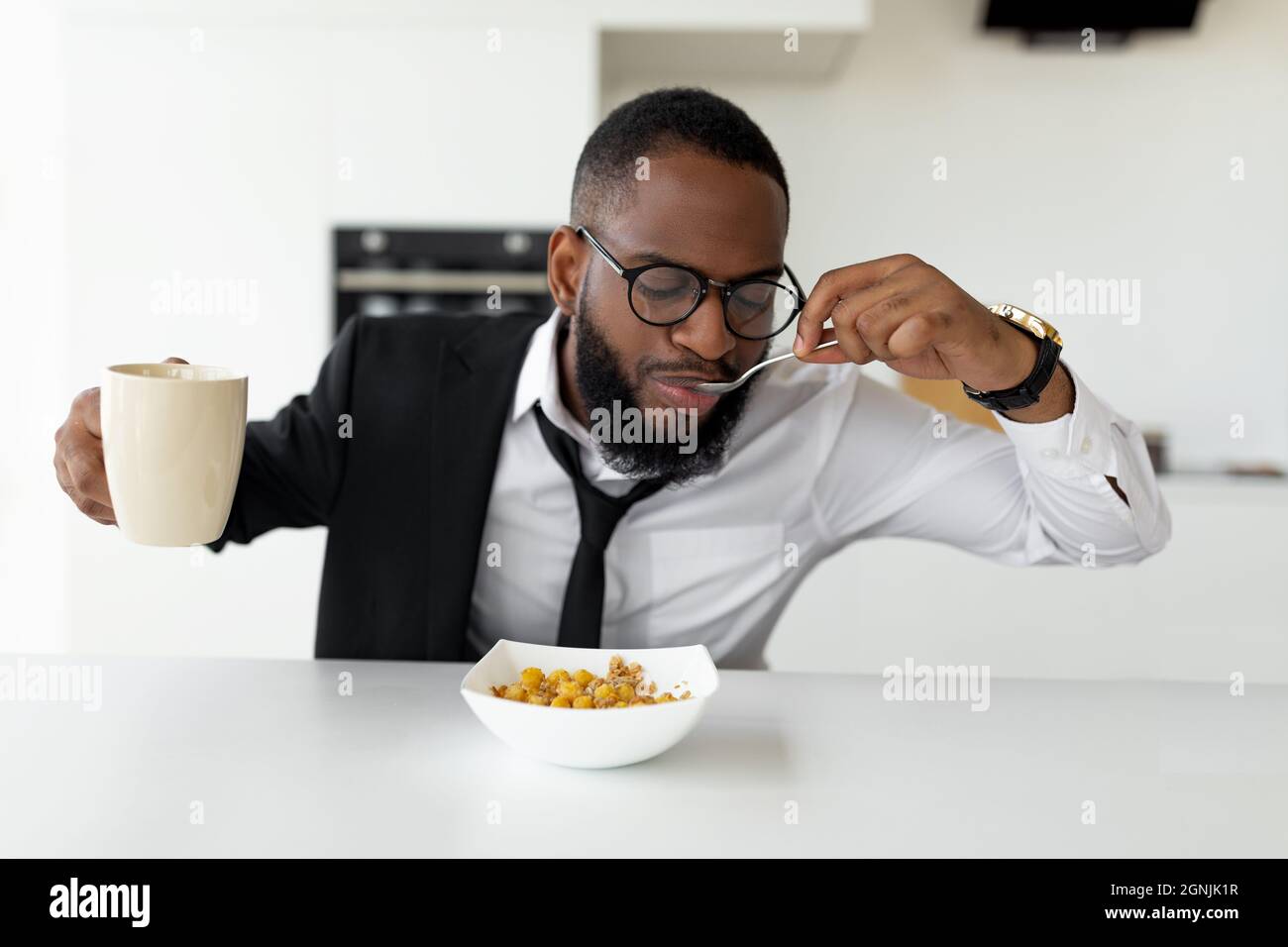 Black man rushing to work eating cereal at home Stock Photo