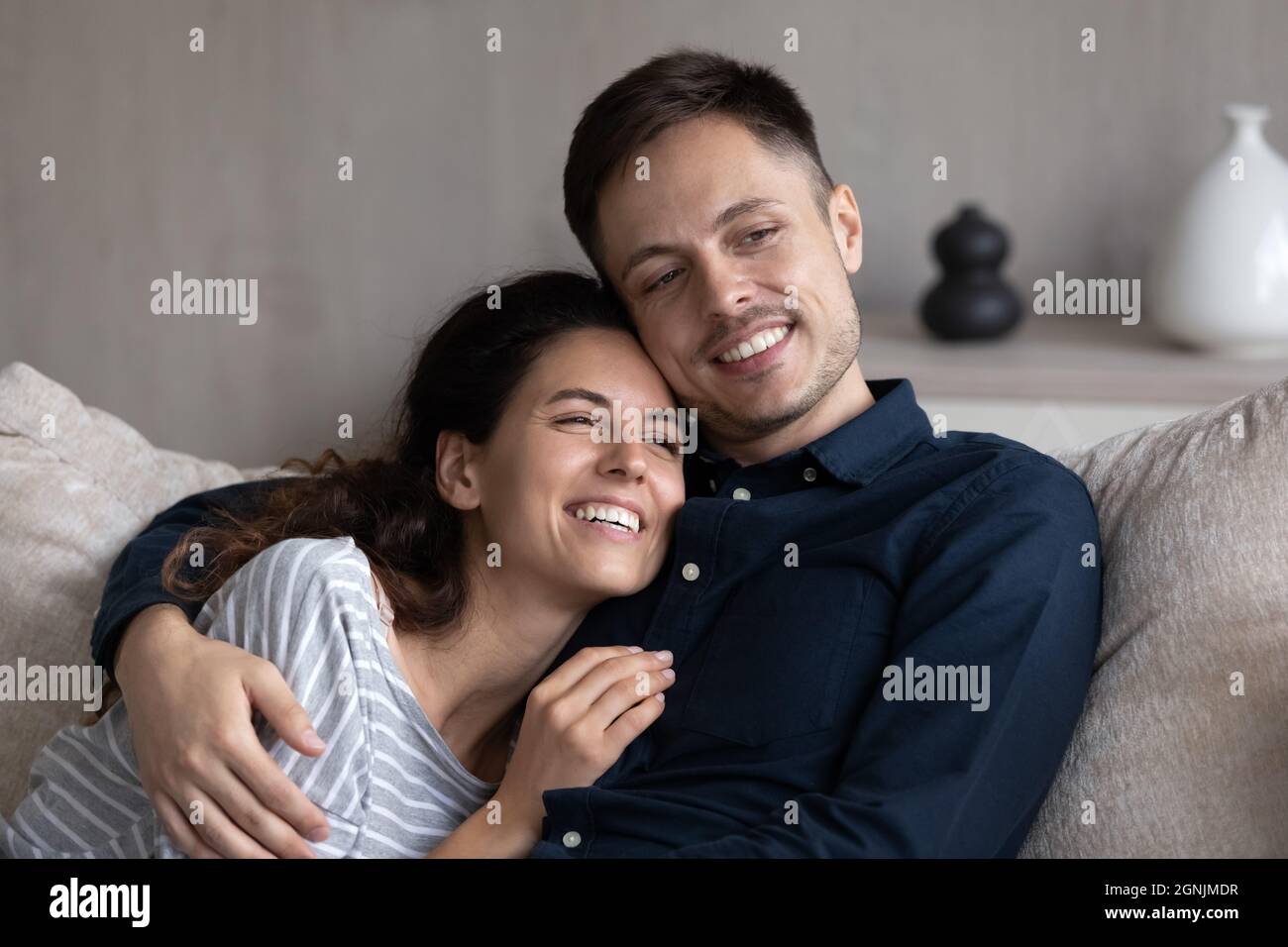 Happy affectionate young hispanic couple daydreaming at home. Stock Photo