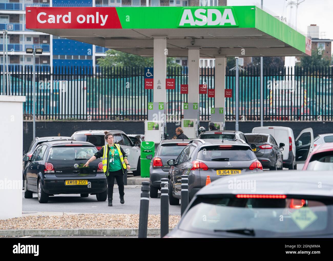 A member of staff directs drivers queuing for fuel at an Asda petrol
