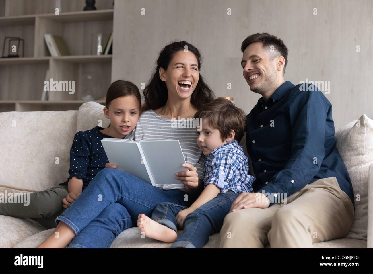 Joyful happy family laughing at funny story, reading book. Stock Photo