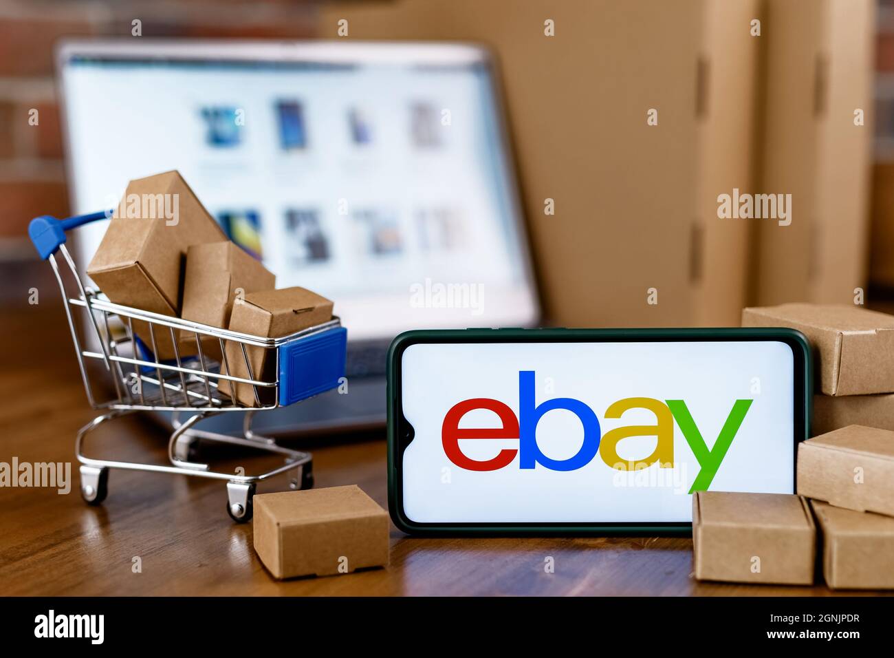 Smartphone with eBay logo on the screen, shopping cart and blurred ...