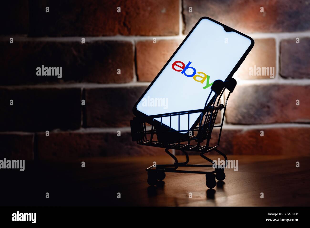 Smartphone with eBay logo on screen in the shopping cart on brick wall
