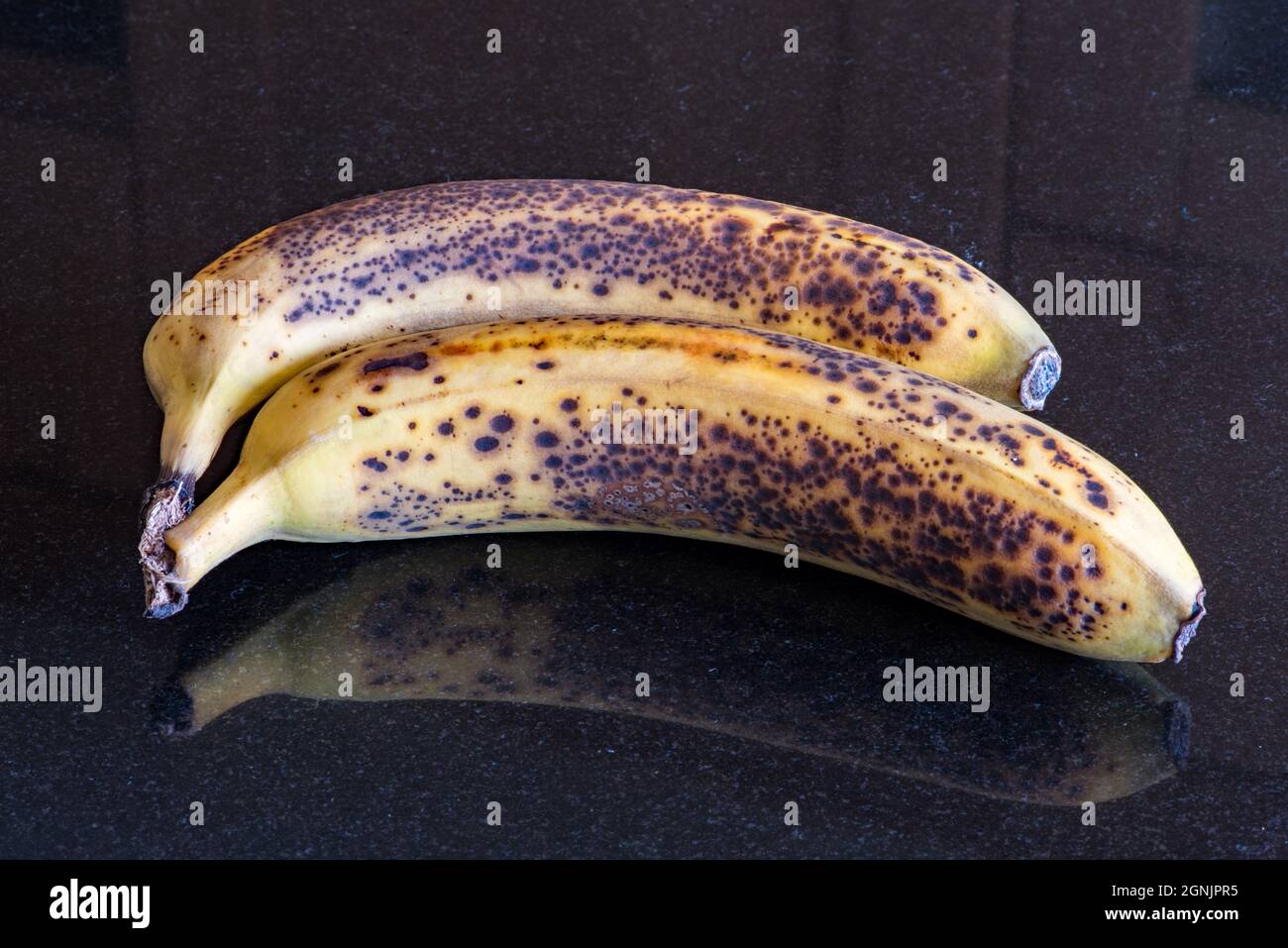 Over-ripe pair pf bananas with dark spotting on the skins Stock Photo