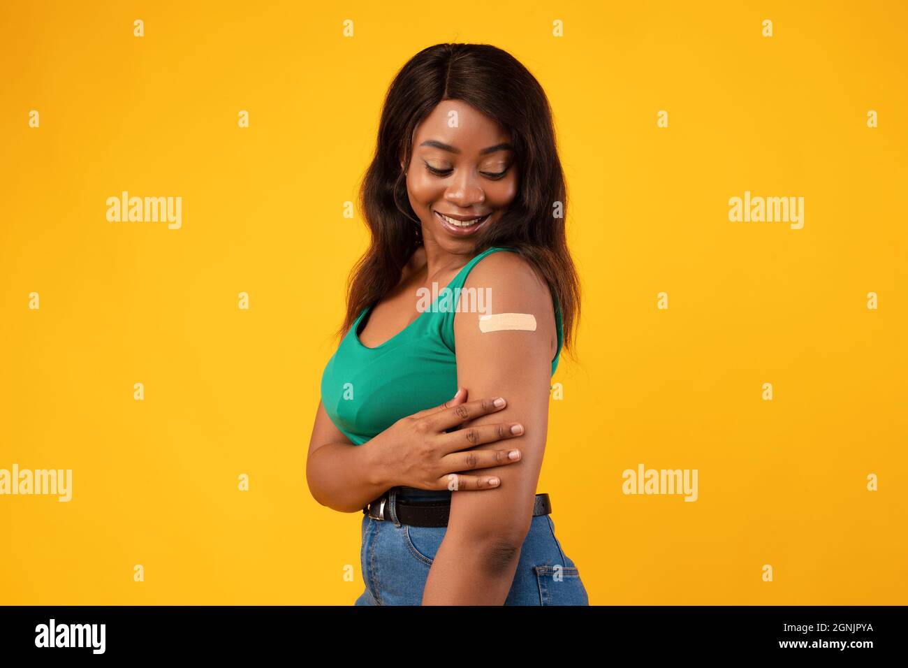 African American Woman Vaccinated Against Covid-19 Showing Arm, Yellow Background Stock Photo