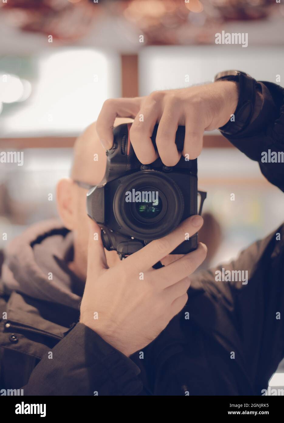 Close up portrait of Man pointing a DSLR camera with bright background Stock Photo