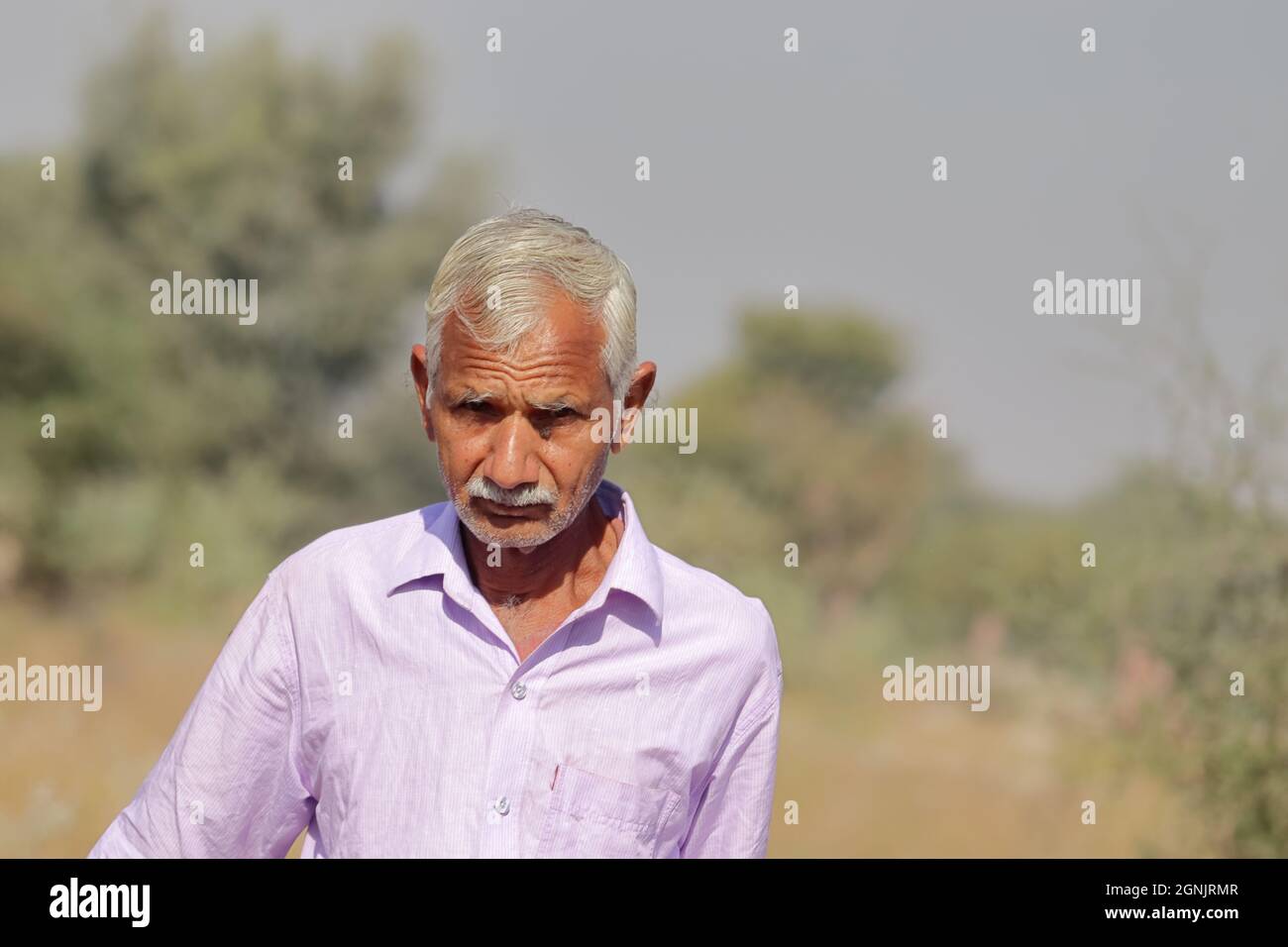 Close-up Photograph of an Indian resident senior man or self-sufficient aged farmer with defocused background of nature or forest Stock Photo