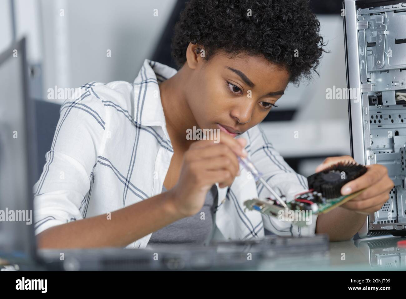 young female computer repairer using screwdriver Stock Photo