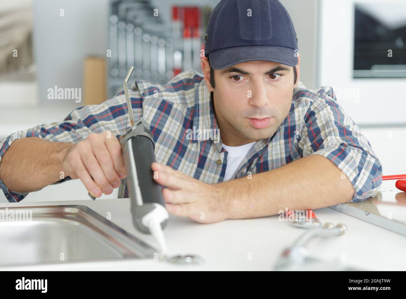 plumber using a silicone tube on a sink Stock Photo
