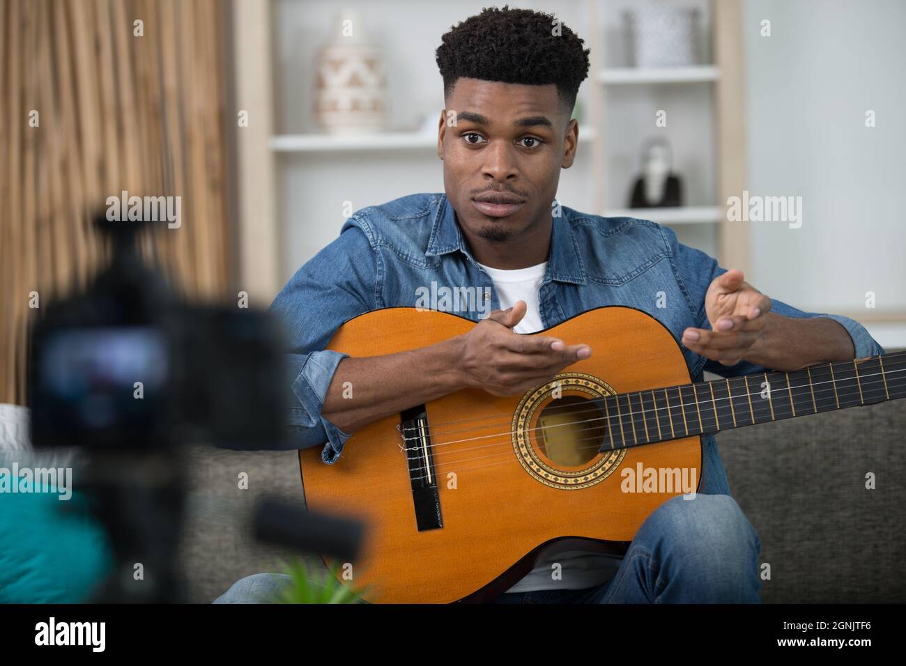 man with guitar filming tutorial for a blog Stock Photo