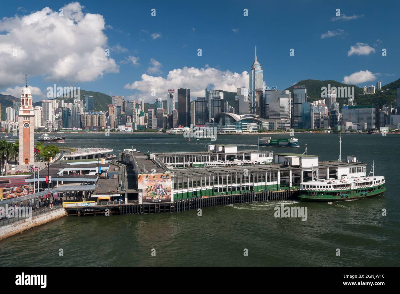 A Star Ferry leaves Tsim Sha Tsui pier in Kowloon, with Wan Chai and Causeway Bay, Hong Kong Island, visible across Victoria Harbour Stock Photo