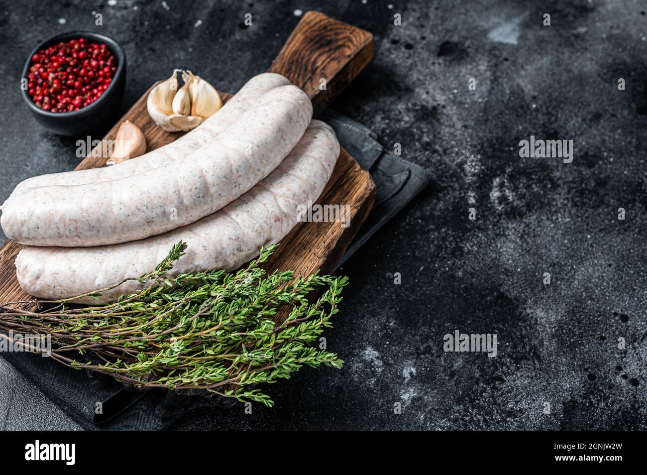 Raw Munich white sausage weisswurst on wooden board. Black background. Top view. Copy space Stock Photo