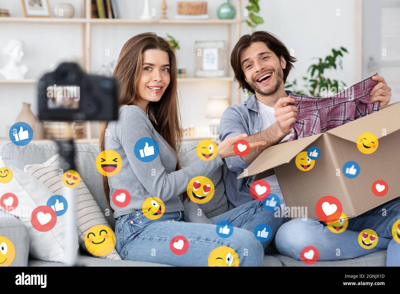 Smiling modern young caucasian bloggers husband and wife unpack box from store and shoot video review Stock Photo