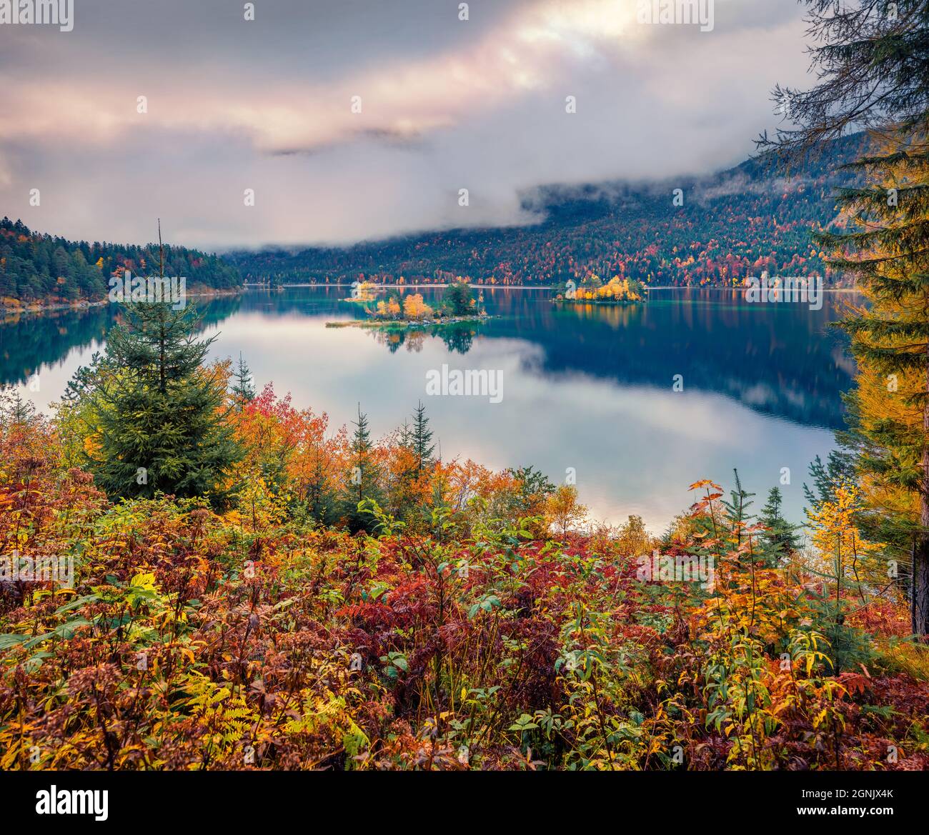 Gloomy morning view of Eibsee lake. Captivating autumn scene of Bavarian Alps, Germany, Europe. Foggy mountain hills reflected in the calm surface of Stock Photo