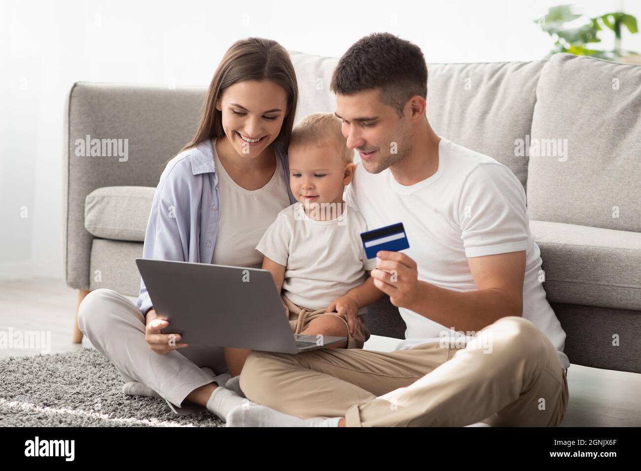 Parents And Little Baby With Laptop And Credit Card Making Online Shopping Stock Photo